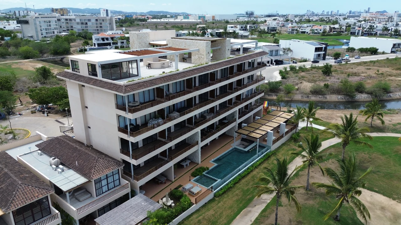 Vista aérea de Mangata Golf & Living: el edificio de condominios y su rooftop frente al campo de golf en Marina Mazatlán